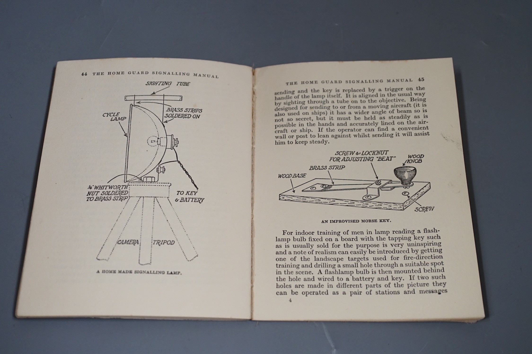 A silver Air Raid Precautions badge and Homeguard signalling manual